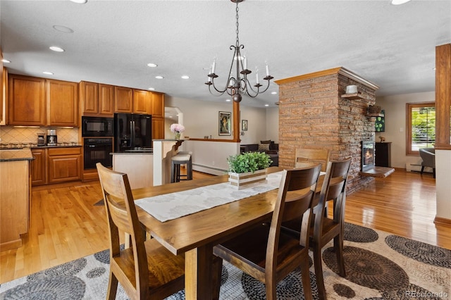 2520 Eldridge Cir, Golden, CO 80401 - dining room with baseboard heating, light wood finished floors, recessed lighting, a fireplace, and a chandelier