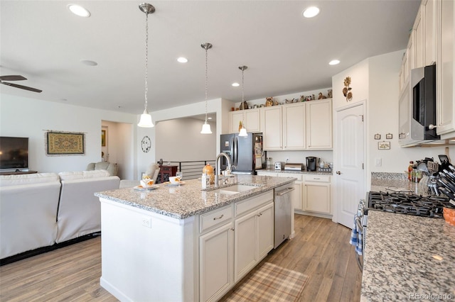 11404 Hannibal St, Commerce City, CO 80022 - kitchen featuring stainless steel appliances, open floor plan, light wood finished floors, an island with sink, and recessed lighting