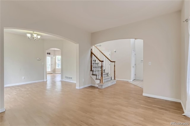 spare room featuring light wood-type flooring and a chandelier