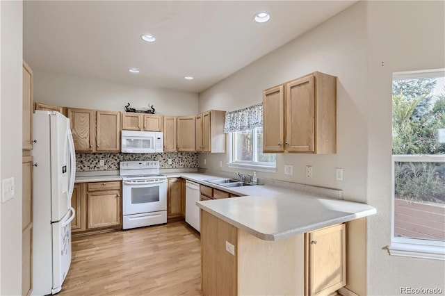 kitchen featuring white appliances, decorative backsplash, sink, light hardwood / wood-style flooring, and kitchen peninsula