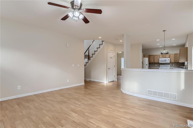 unfurnished living room featuring ceiling fan and light wood-type flooring