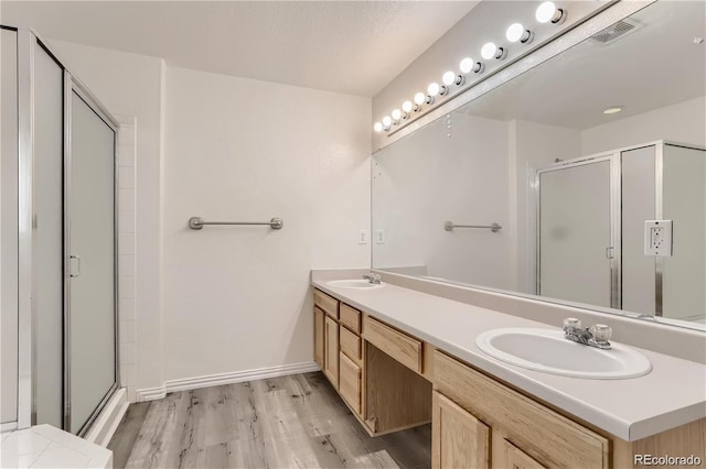 bathroom featuring dual vanity, wood-type flooring, and walk in shower