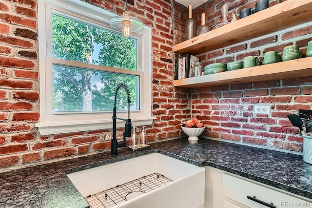 3955 S Nucla St, Aurora, CO 80013 - kitchen with brick wall, open shelves, white cabinets, and dark stone counters