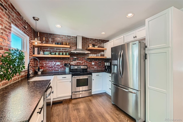3955 S Nucla St, Aurora, CO 80013 - kitchen featuring stainless steel appliances, wall chimney exhaust hood, open shelves, white cabinets, and brick wall