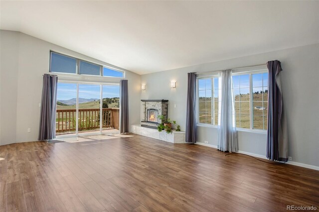 1536 County Road 1, Cripple Creek, CO 80813 - unfurnished living room featuring lofted ceiling, a fireplace, wood finished floors, a mountain view, and baseboards