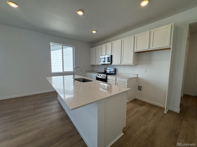 6170 Amerifax Dr, Windsor, CO 80528 - kitchen with stainless steel appliances, white cabinets, an island with sink, wood finished floors, and recessed lighting