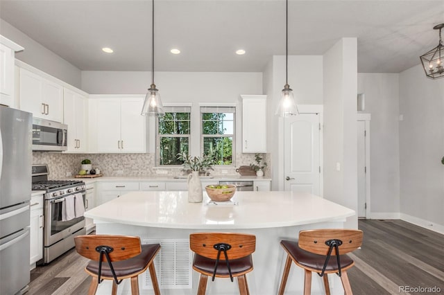 5735 Boston St, Denver, CO 80238 - kitchen with appliances with stainless steel finishes, a kitchen bar, dark wood-style floors, decorative backsplash, and recessed lighting