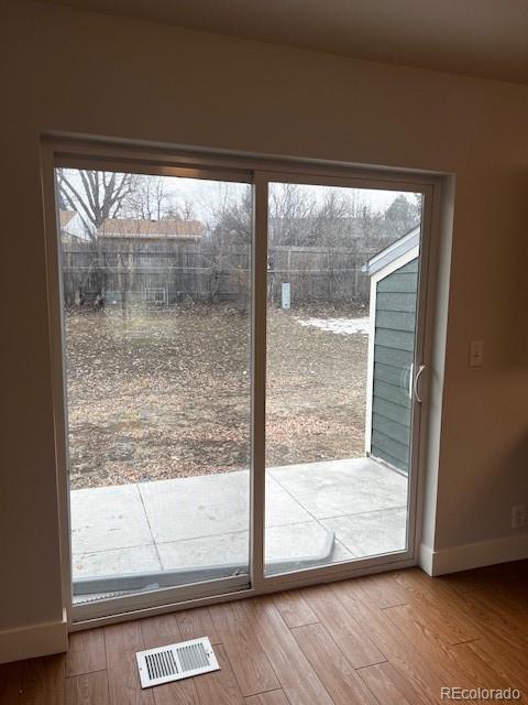 entryway with baseboards, visible vents, and wood finished floors