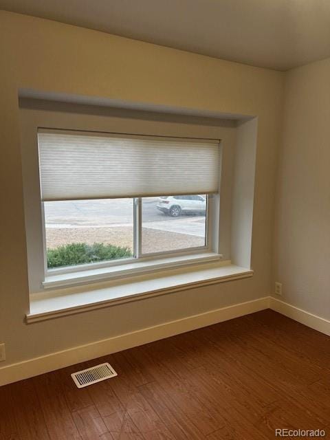 unfurnished room with dark wood finished floors, visible vents, and baseboards