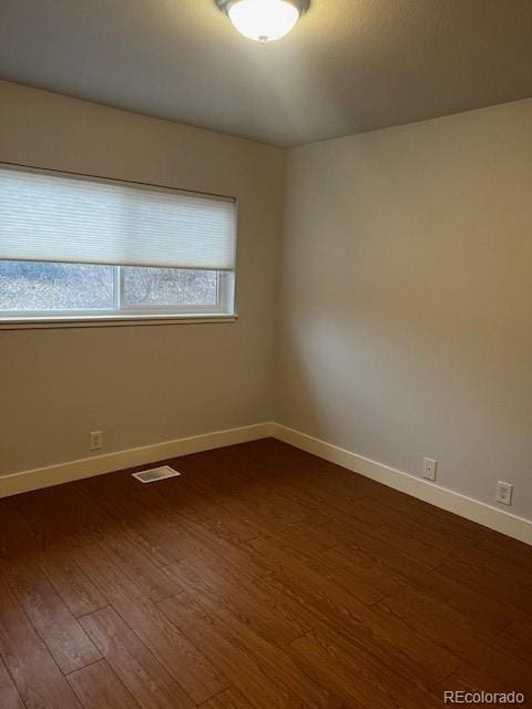 empty room with visible vents, baseboards, and dark wood-style flooring