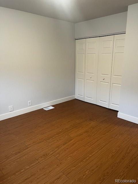 unfurnished bedroom with baseboards, dark wood finished floors, and a closet