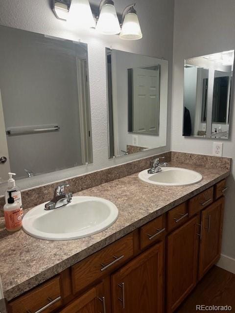 bathroom with double vanity, a sink, and wood finished floors