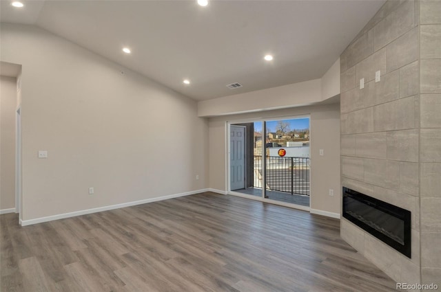 unfurnished living room with hardwood / wood-style floors, a fireplace, and vaulted ceiling