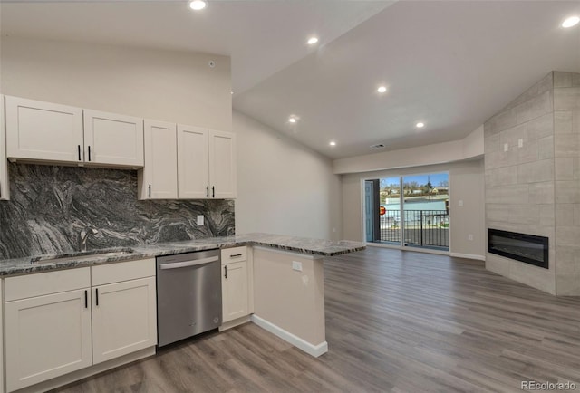 kitchen with stainless steel dishwasher, kitchen peninsula, and white cabinetry