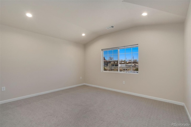 carpeted spare room featuring vaulted ceiling