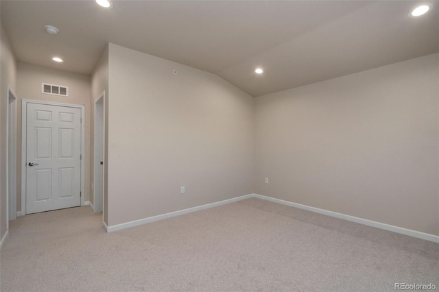 unfurnished room featuring lofted ceiling and light colored carpet