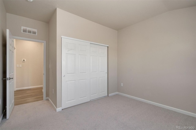 unfurnished bedroom with lofted ceiling, a closet, and carpet floors