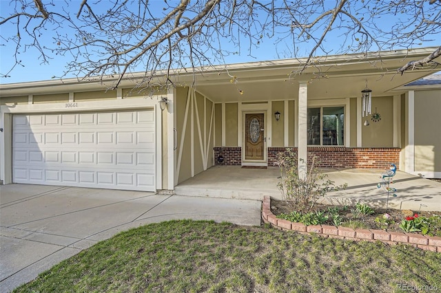 ranch-style home with driveway, an attached garage, a porch, stucco siding, and brick siding