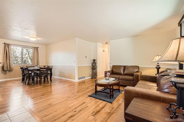 living room featuring light wood-style floors, visible vents, and baseboards