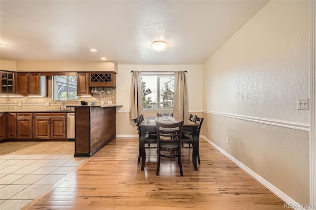 dining area featuring light wood finished floors, a textured wall, and baseboards