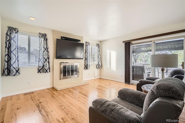 living room featuring recessed lighting, visible vents, baseboards, light wood-style flooring, and a brick fireplace