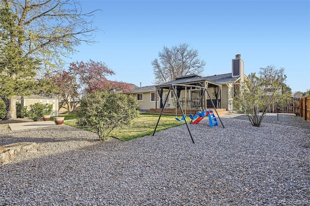 view of front of property featuring a gazebo, a chimney, fence, a playground, and a front yard