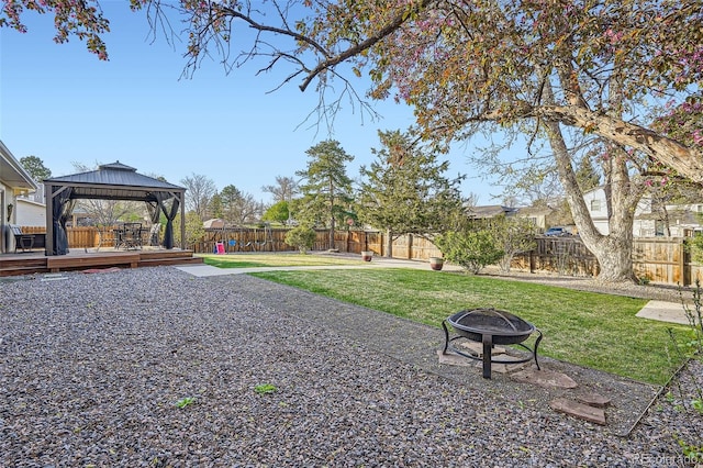 view of property's community featuring a fenced backyard, a yard, a wooden deck, a fire pit, and a gazebo