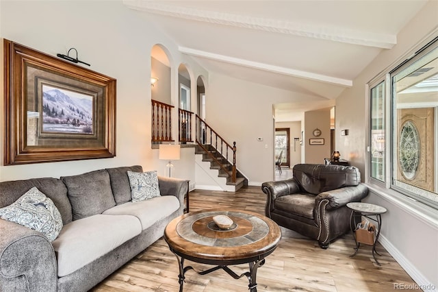 6238 S Cherry Cir, Centennial, CO 80121 - living area with arched walkways, light wood-style flooring, baseboards, vaulted ceiling with beams, and stairway