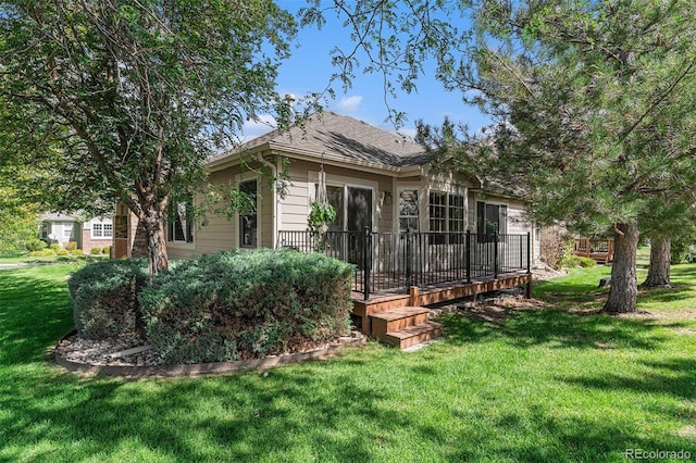 rear view of house featuring a wooden deck and a lawn