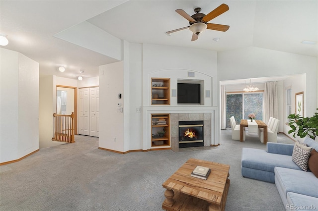 carpeted living room with ceiling fan with notable chandelier, lofted ceiling, and a tile fireplace