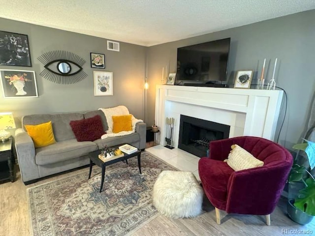 12546 E Cornell Ave Unit 104, Aurora, CO 80014 - living area featuring wood finished floors, a textured ceiling, and a tiled fireplace
