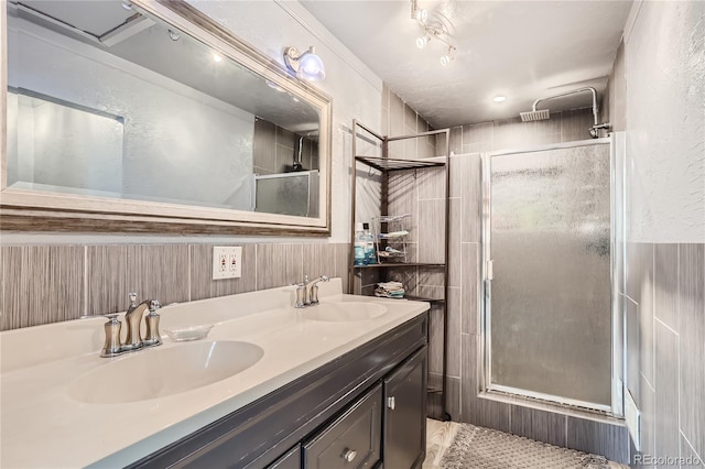 bathroom with tile patterned flooring, tile walls, an enclosed shower, and vanity