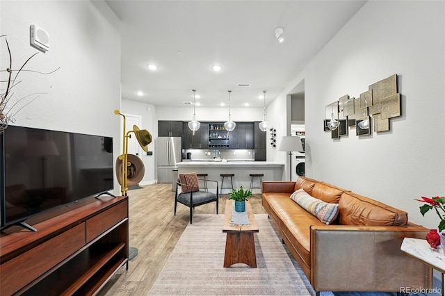 living room featuring light wood-style flooring, washer / dryer, and recessed lighting