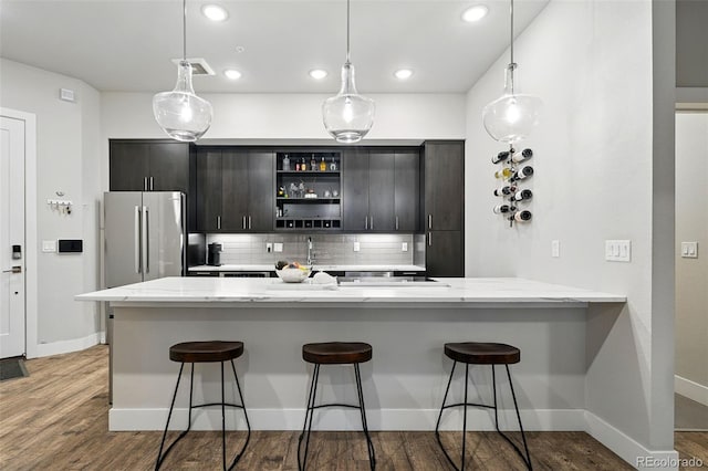 kitchen with freestanding refrigerator, backsplash, open shelves, a kitchen breakfast bar, and wood finished floors