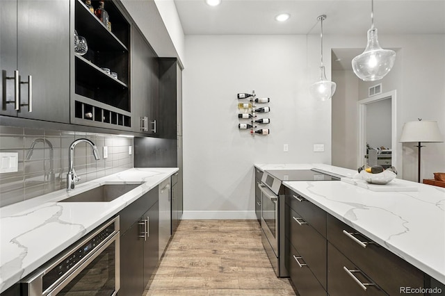 kitchen featuring a sink, stainless steel electric range oven, built in microwave, light wood-style floors, and baseboards