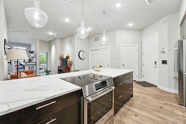 kitchen featuring appliances with stainless steel finishes, light wood-type flooring, decorative light fixtures, dark brown cabinets, and baseboards