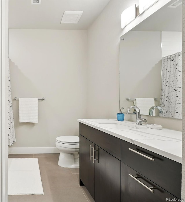 bathroom with tile patterned flooring, toilet, vanity, and baseboards