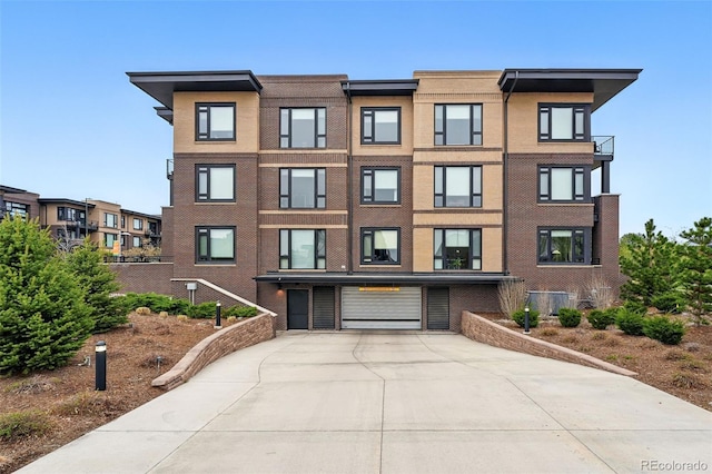 view of building exterior featuring an attached garage, driveway, and cooling unit