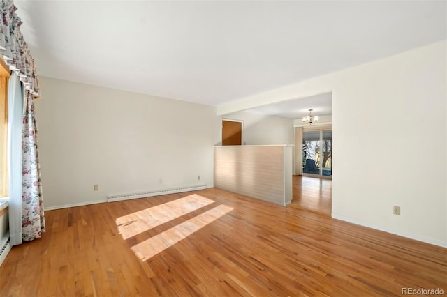 spare room featuring a chandelier, a baseboard radiator, and light hardwood / wood-style flooring