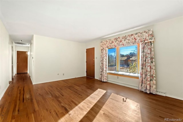 spare room with dark wood-type flooring and a baseboard heating unit