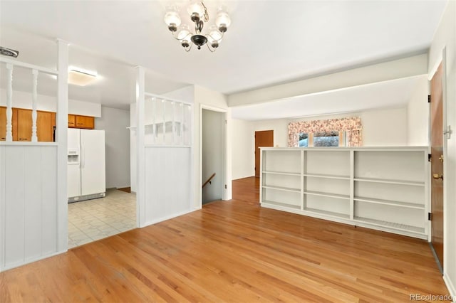 spare room with light wood-type flooring and a notable chandelier