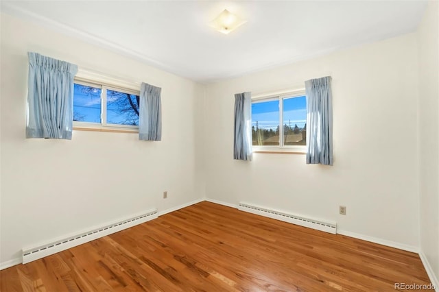 empty room with hardwood / wood-style flooring and a baseboard heating unit