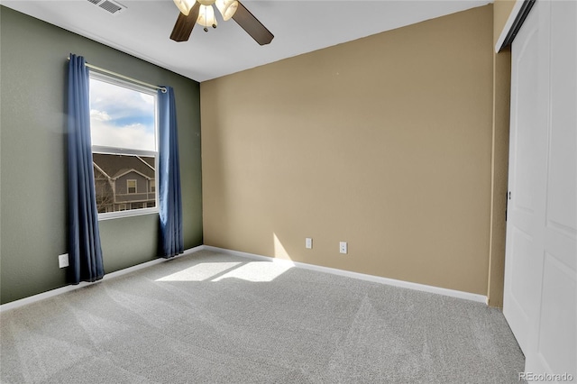 empty room featuring ceiling fan, carpet floors, visible vents, and baseboards