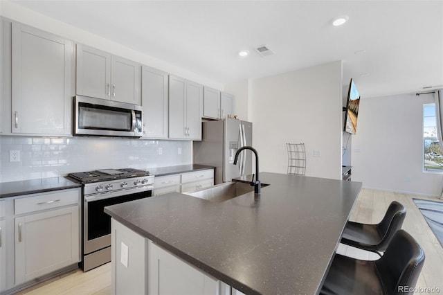 kitchen with a breakfast bar area, a kitchen island with sink, sink, and stainless steel appliances