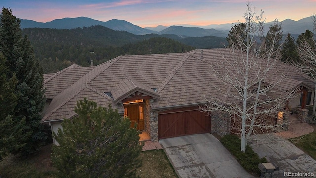 1015 Nob Hill Rd, Evergreen, CO 80439 - view of front of property with stone siding, an attached garage, driveway, and a mountain view