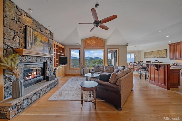 1015 Nob Hill Rd, Evergreen, CO 80439 - living area featuring lofted ceiling, a ceiling fan, a stone fireplace, and light wood-style flooring