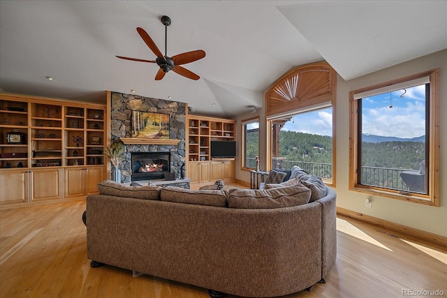 1015 Nob Hill Rd, Evergreen, CO 80439 - living room with vaulted ceiling, a stone fireplace, light wood-type flooring, built in shelves, and ceiling fan