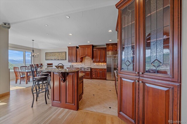 1015 Nob Hill Rd, Evergreen, CO 80439 - kitchen featuring recessed lighting, stainless steel appliances, premium range hood, decorative backsplash, and a breakfast bar area
