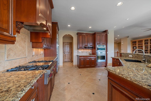 1015 Nob Hill Rd, Evergreen, CO 80439 - kitchen featuring arched walkways, a sink, recessed lighting, decorative backsplash, and appliances with stainless steel finishes
