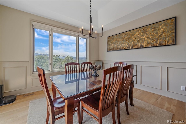1015 Nob Hill Rd, Evergreen, CO 80439 - dining space with light wood-type flooring, plenty of natural light, a chandelier, and a decorative wall